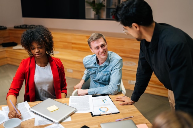 Side view of successful business team leader standing surrounded by diverse colleagues confidently looking to staff Multiethnic startup business team posing