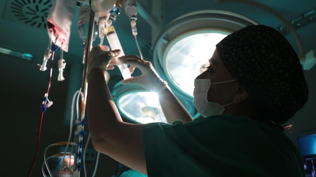 Foto vista laterale di un chirurgo che tiene in mano una percolazione endovenosa in sala operatoria
