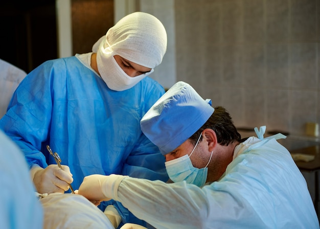 Side view of the surgeon performing the operation, next to his assistant