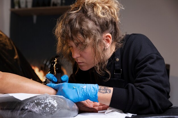 Tatuatore di vista laterale che fa il suo lavoro