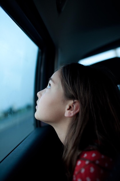 車の窓から見る思慮深い女の子のサイドビュー
