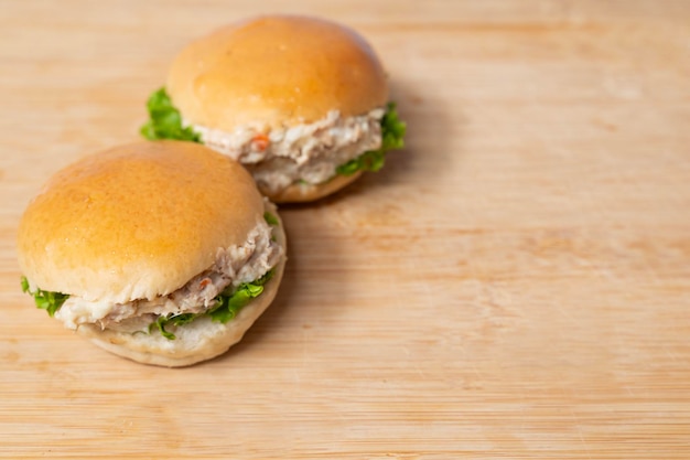 Photo side view of tuna burgers on wooden table