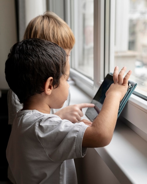 Side view of two boys playing on tablet at home