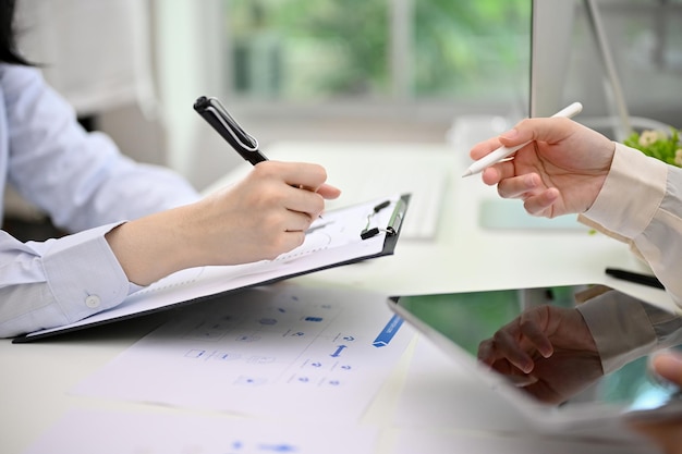 side view of two businesswomen analyzing financial data on report together in the office
