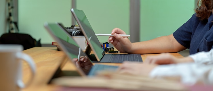 Photo side view of two female worker working together with digital tablets