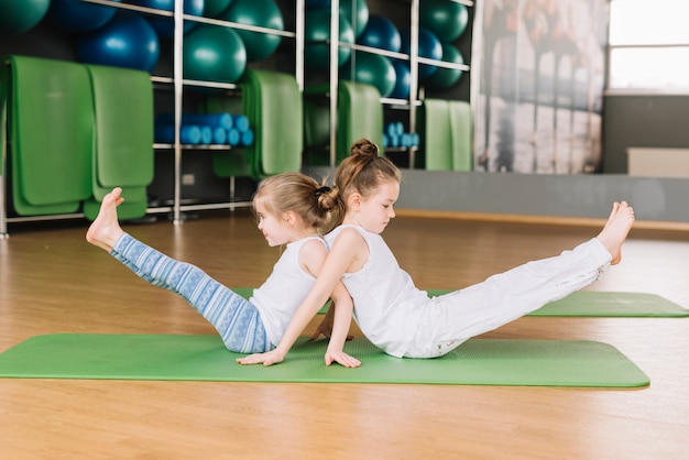 Una vista laterale di due piccole bambine che fanno esercizi di yoga