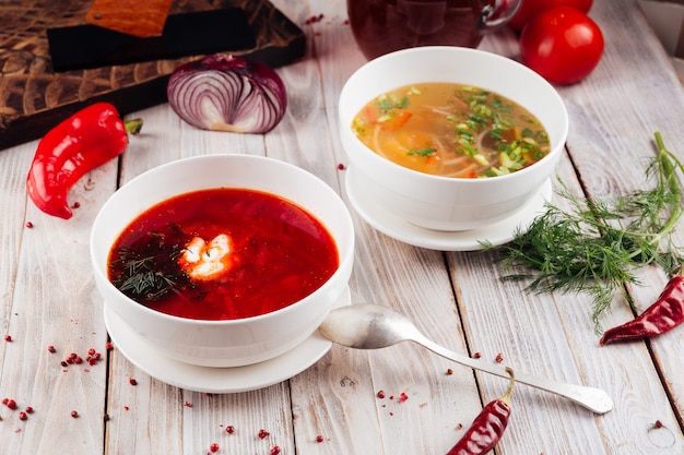 Side view on two soups borsch and vegetable on the light wooden table