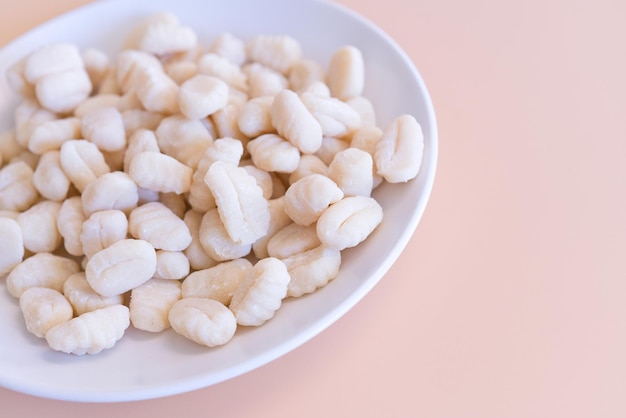 A side view of an uncooked Gnocchi lays on a white plate on a yellow background Flour Italian Pasta Raw Meal Cooking Homemade White Healthy Dinner Fresh Ingredient