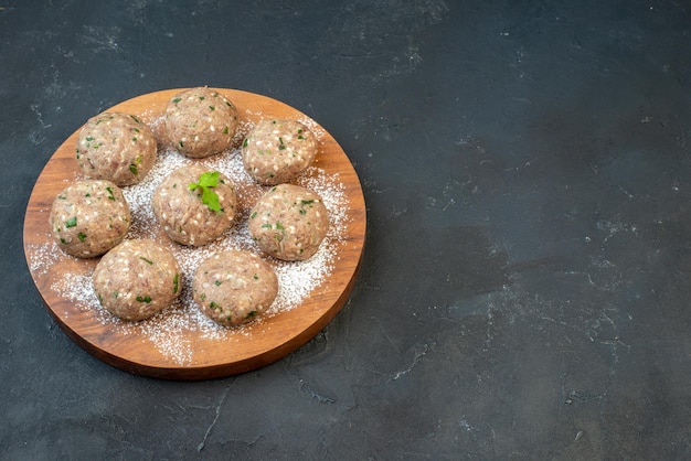 Side view of uncooked meat balls with green in a brown plate on the right side on black background with free space