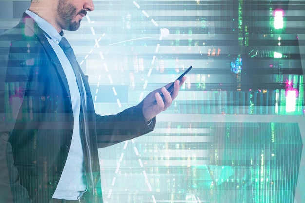 Side view of unrecognizable businessman looking at smartphone standing over night cityscape background with graphs. Toned image double exposure