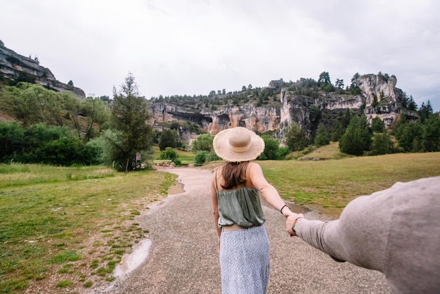 Foto vista laterale di una donna irriconoscibile che tira la mano del suo ragazzo facendo una passeggiata nella natura. vista orizzontale della donna che viaggia nel canyon del fiume lobos a soria. persone e destinazioni di viaggio in spagna.