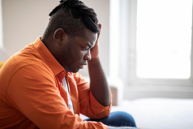 side view of upset african american guy sitting at home