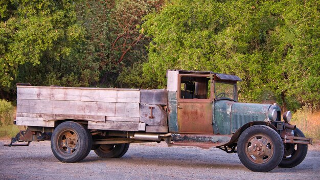 Photo side view of a vehicle on road against trees