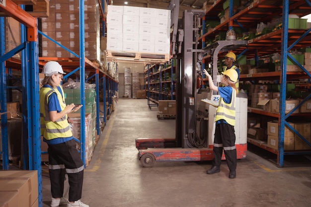 Side view of warehouse workers discussing inspecting goods brought into the warehouse