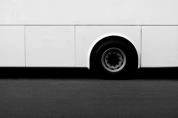 Side view of a white bus wheel on an asphalt road. 