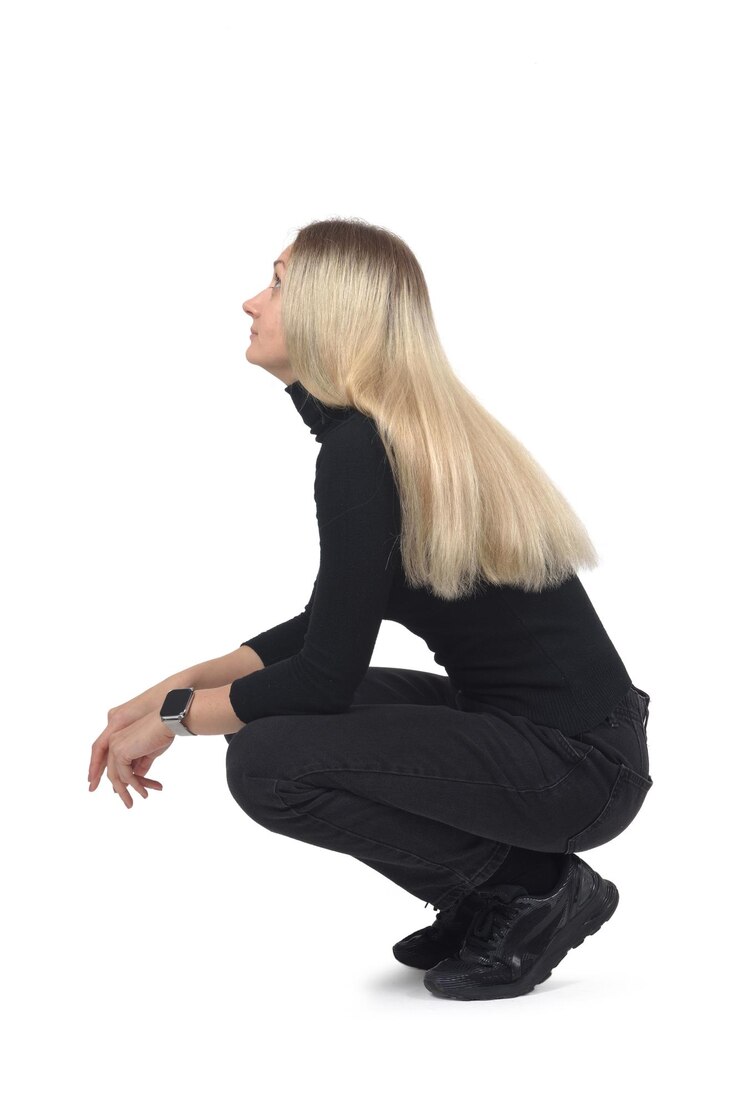 side view of a woaman sitting on her haunches look up on white background