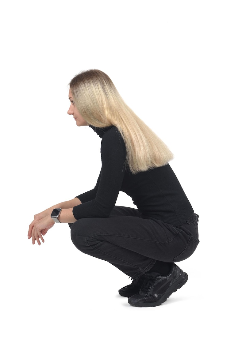 side view of a woaman sitting on her haunches on white background