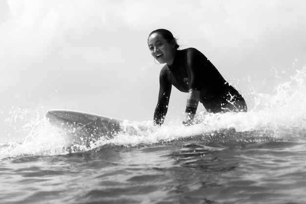 Photo side view of womamln sitting on a surfboard