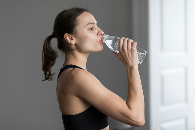 Side view of woman in activewear drinking water