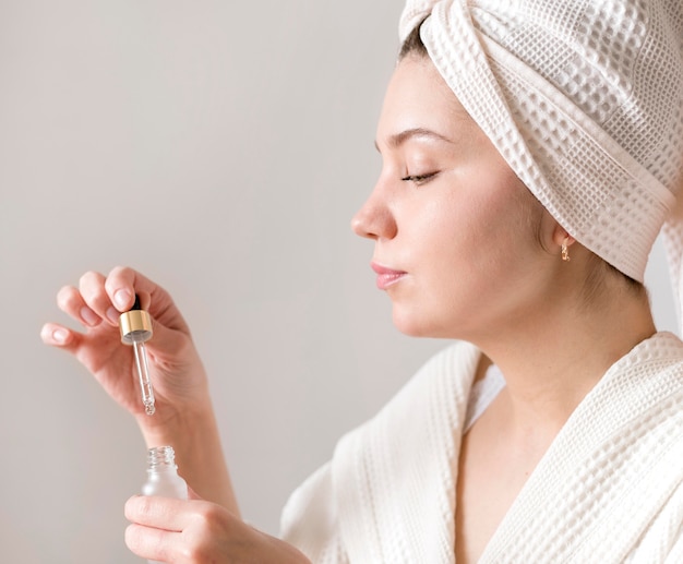 Side view woman applying face serum