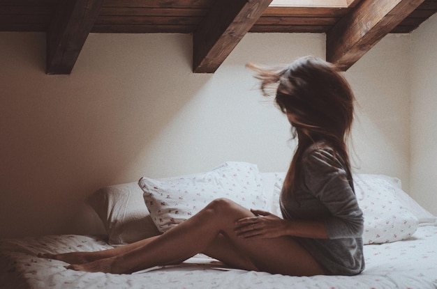 Side view of woman on bed at home