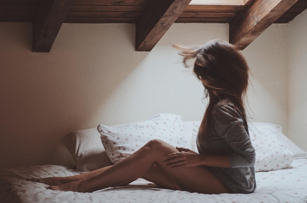 Photo side view of woman on bed at home