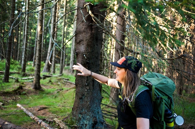 Side view of woman by tree trunk in forest