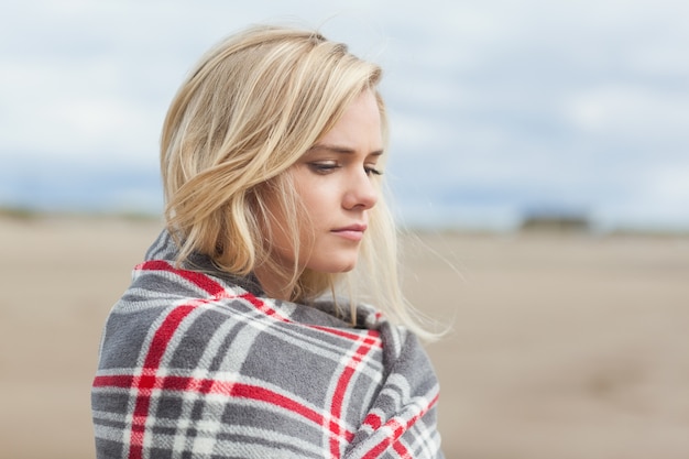 Photo side view of a woman covered with blanket at beach