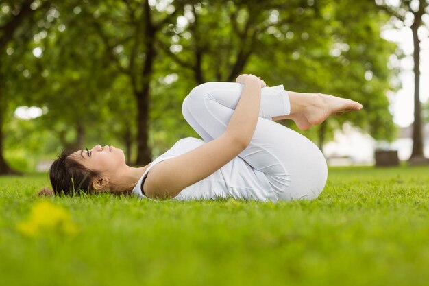 La vista laterale della donna che fa l'allungamento si esercita in parco