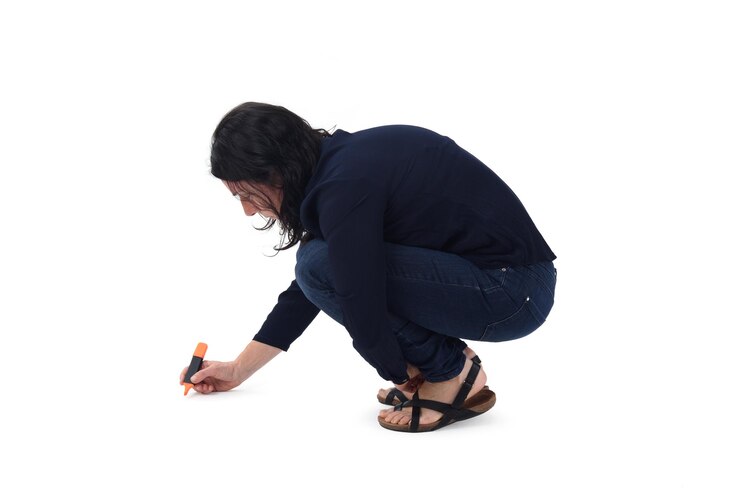 side view of a woman drawing or writing on the floor with a marker on white background