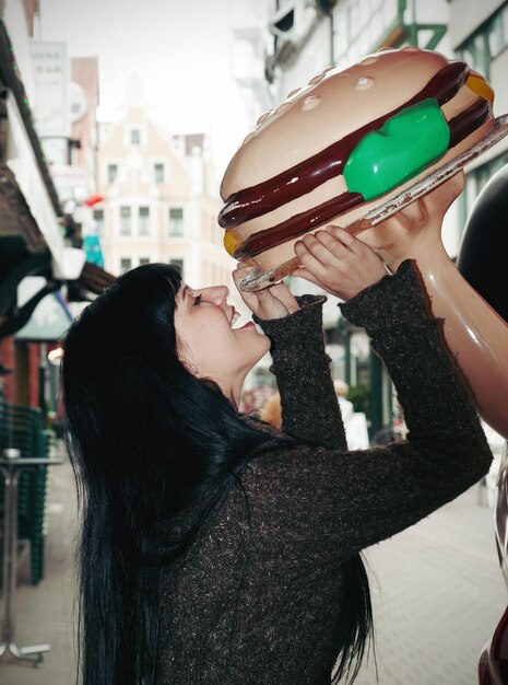 Foto vista laterale di una donna che mangia un burger artificiale