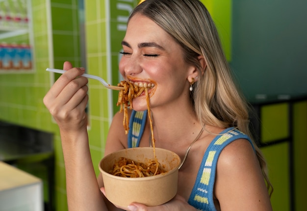 Foto donna di vista laterale che mangia pasta in un modo divertente