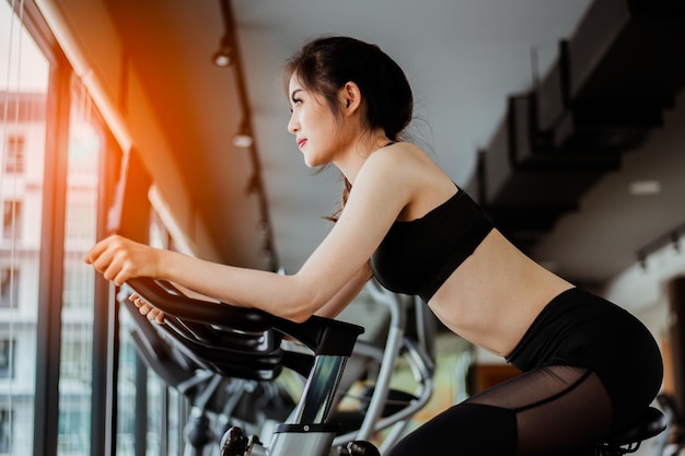 Side view of woman exercising on bike in gym