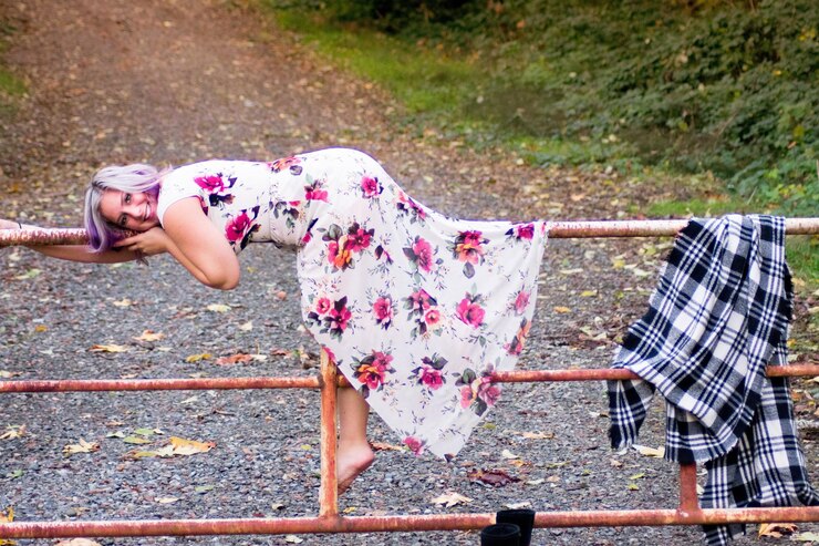Photo side view of woman in floral dress lying on gate