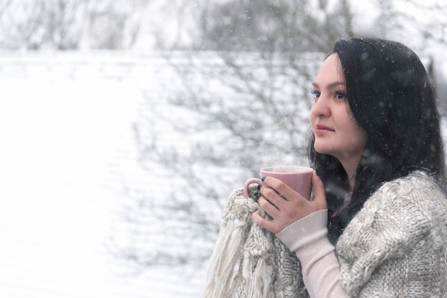 Foto vista laterale di una donna che beve durante la nevicata