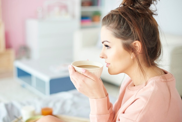 朝のコーヒーを飲んでいる女性の側面図