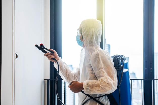 Side view of woman holding camera while standing against window