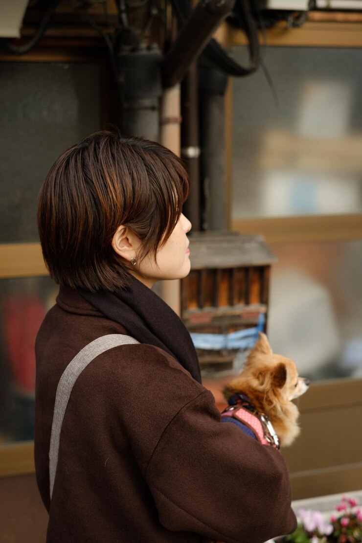 Photo 外に立っている犬を抱いている女性のサイドビュー