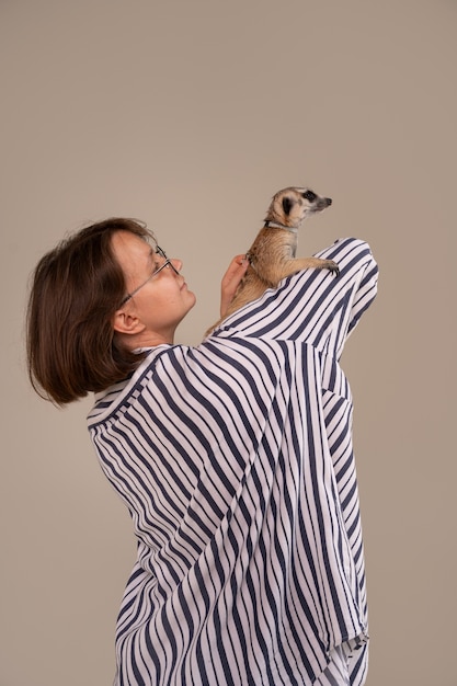 Photo side view woman holding meerkat