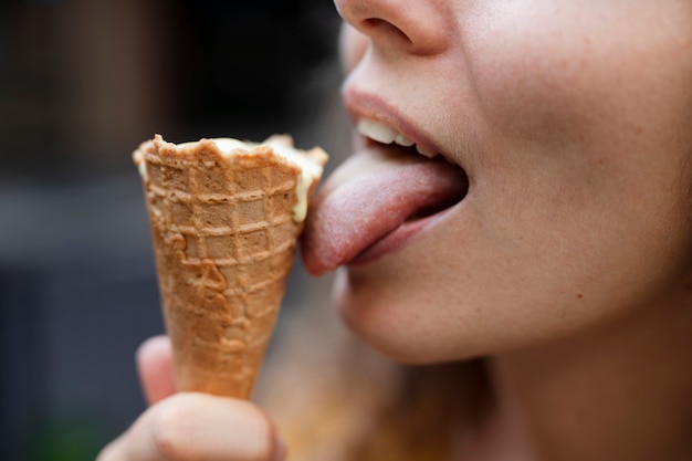 Foto donna di vista laterale che lecca il cono gelato