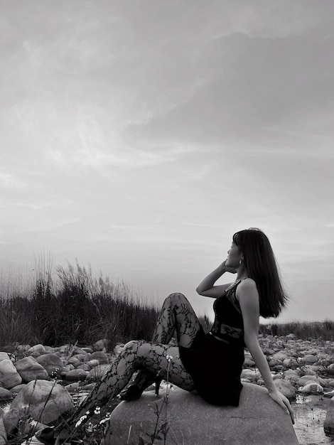 Foto vista laterale di una donna che guarda il mare contro il cielo