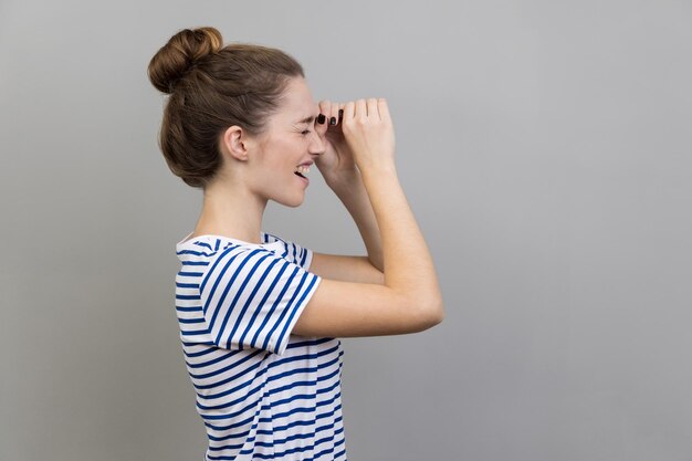 Side view of woman looking through monocular gesture and expressing positive emotions