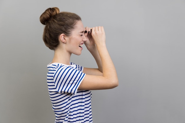 Side view of woman looking through monocular gesture and expressing positive emotions