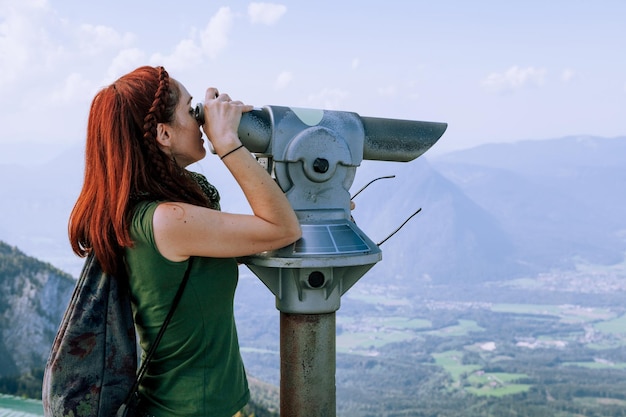 Photo side view of woman looking through telescope while standing against sky