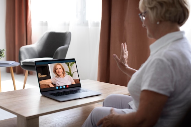 Foto vista laterale donna che effettua una videochiamata