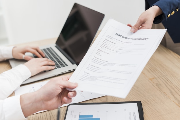 Side view of woman offering contract during job interview