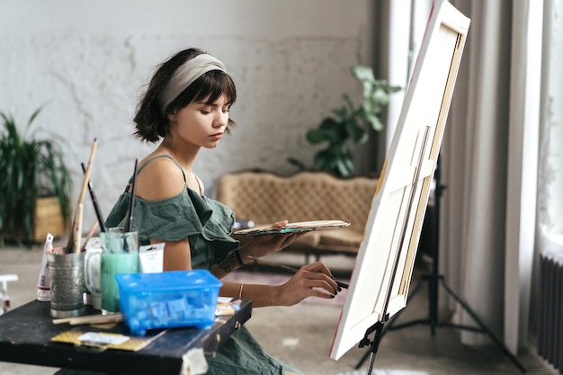 Photo side view of woman painting on canvas at art studio