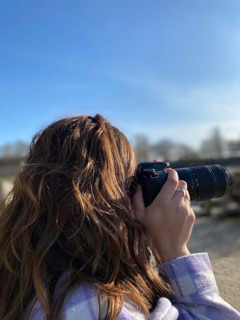 Foto vista laterale di una donna che fotografa contro il cielo