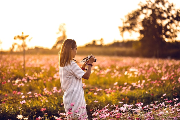 Side view of woman photographing on field during sunset