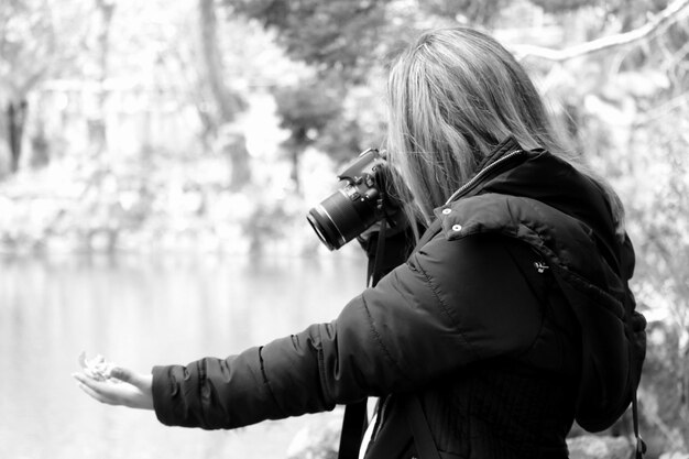 Foto vista laterale di una donna che fotografa in un parco